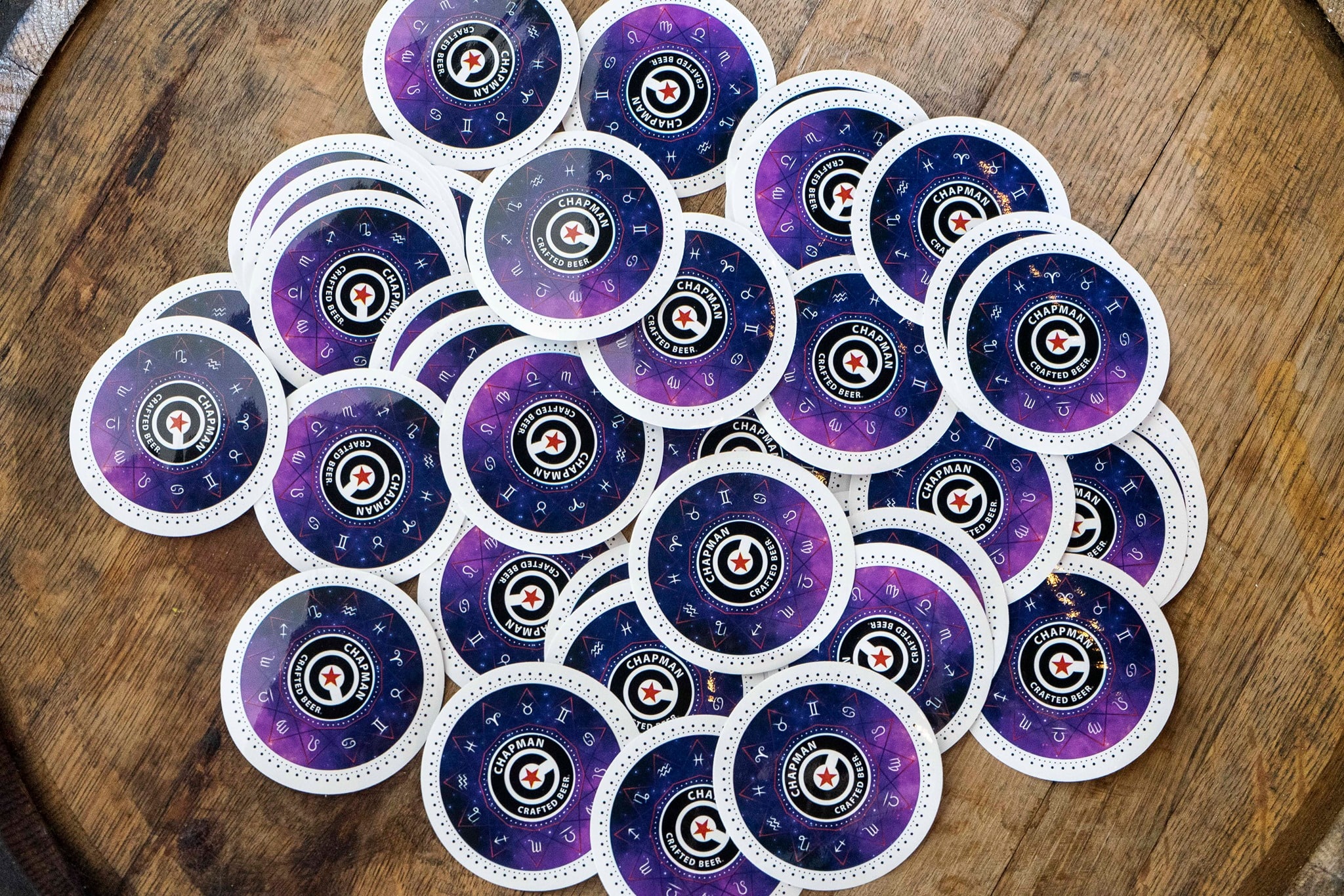 Zodiac Series merchandise — branded coasters spread on a wooden barrel